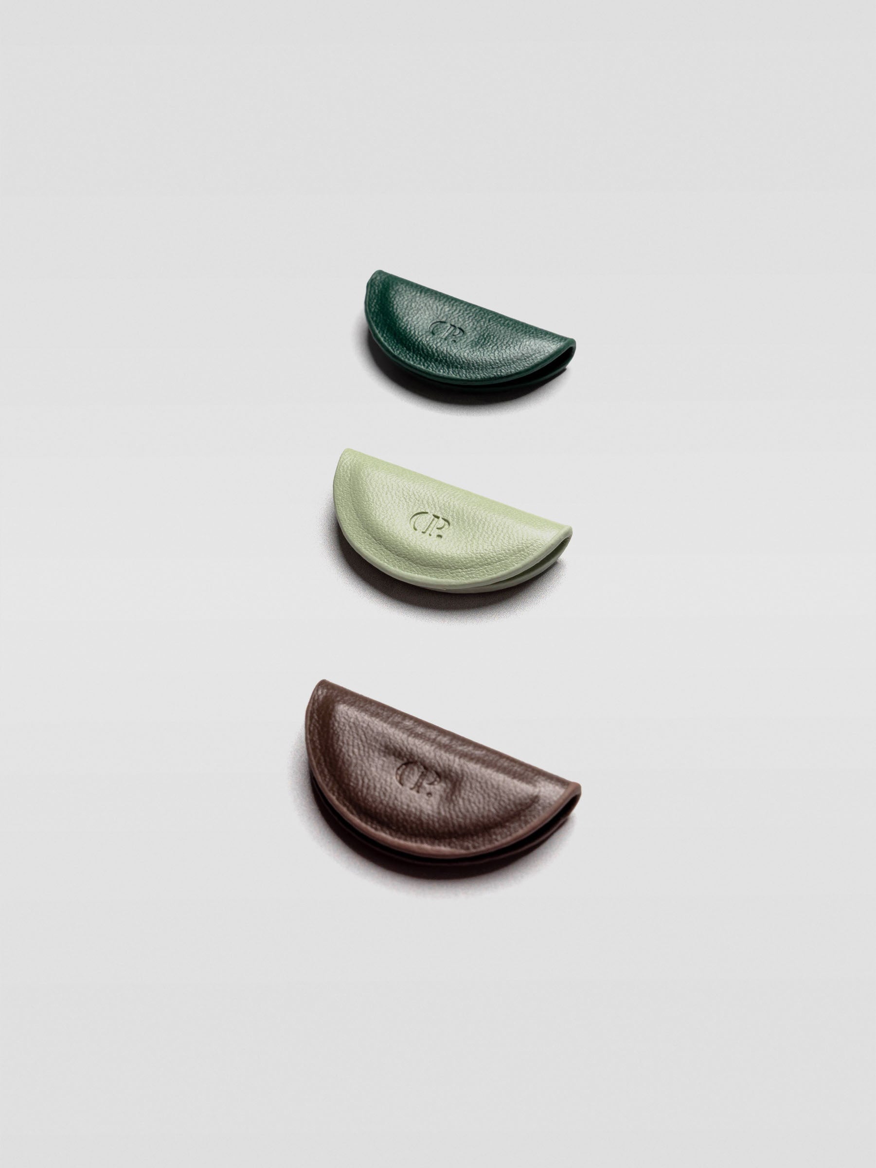 Angled view of the three half-moon bookmarks stacked in a staggered formation to show their thickness and texture, emphasizing the CP debossed logo.