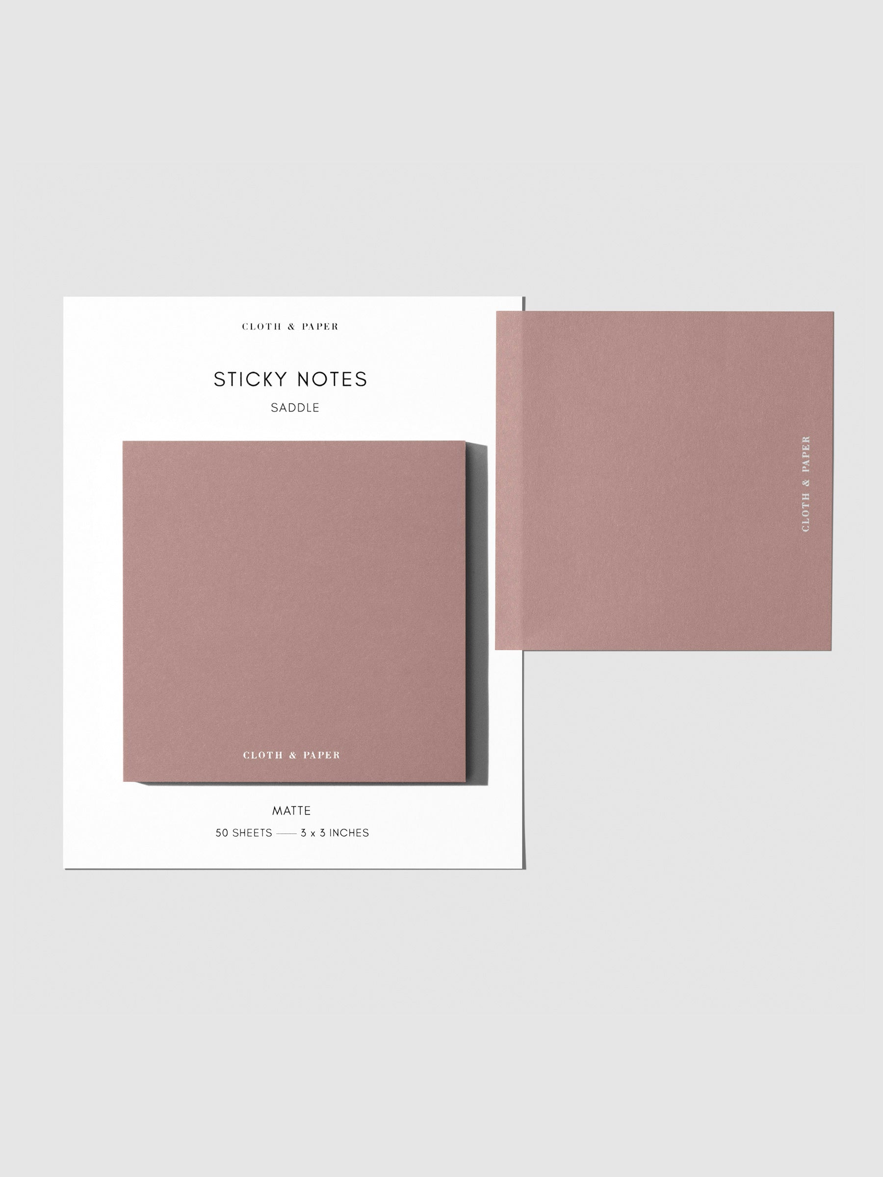 Sticky note set displayed against a neutral background. One note is placed on the packaging's edge. Color shown is Saddle.