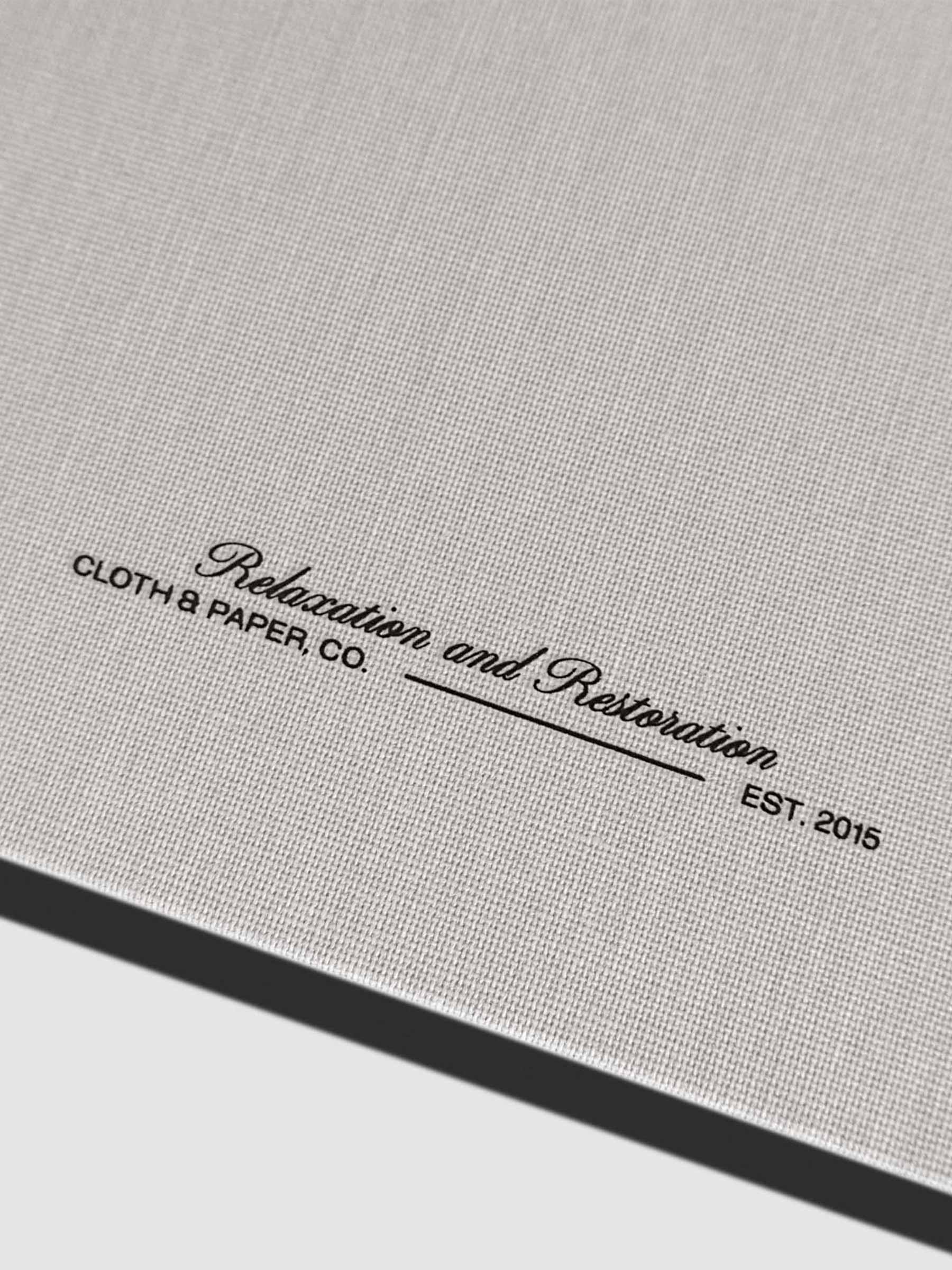 Closeup of fabric detailing and Rilassati tagline printed on folio. Text reads "Relaxation and Restoration / Cloth & Paper Co. / Est. 2015"