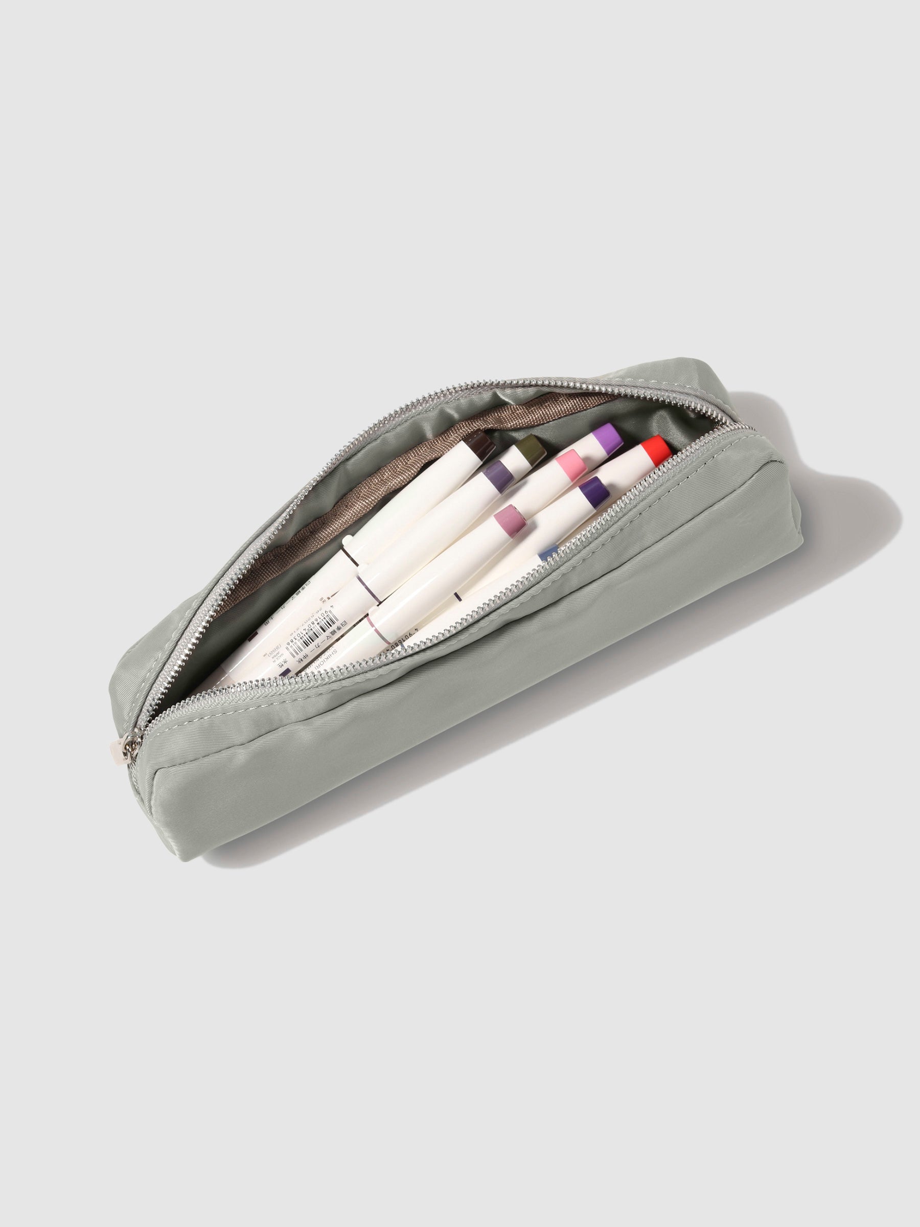 Ristretto pencil pouch displayed open on a neutral background. A collection of pens are inside the pouch. 