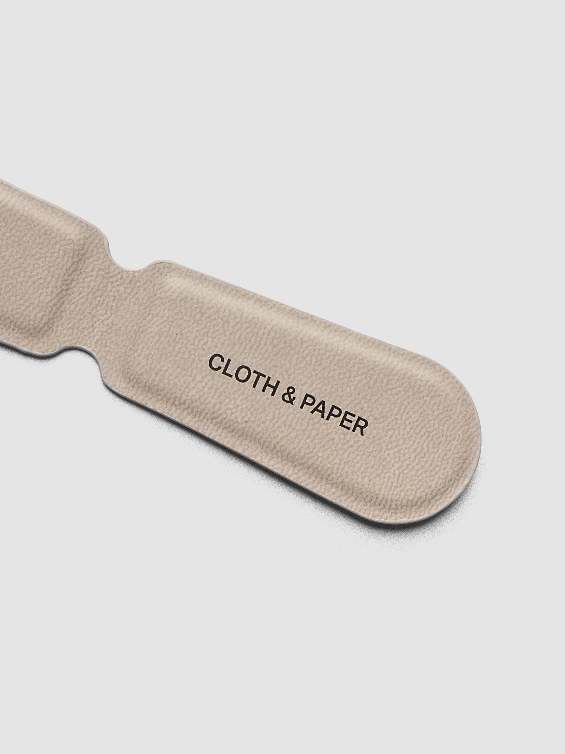 Magnetic Bookmark Smooth Leather in light taupe placed on a lined notebook page beside a black leather notebook cover