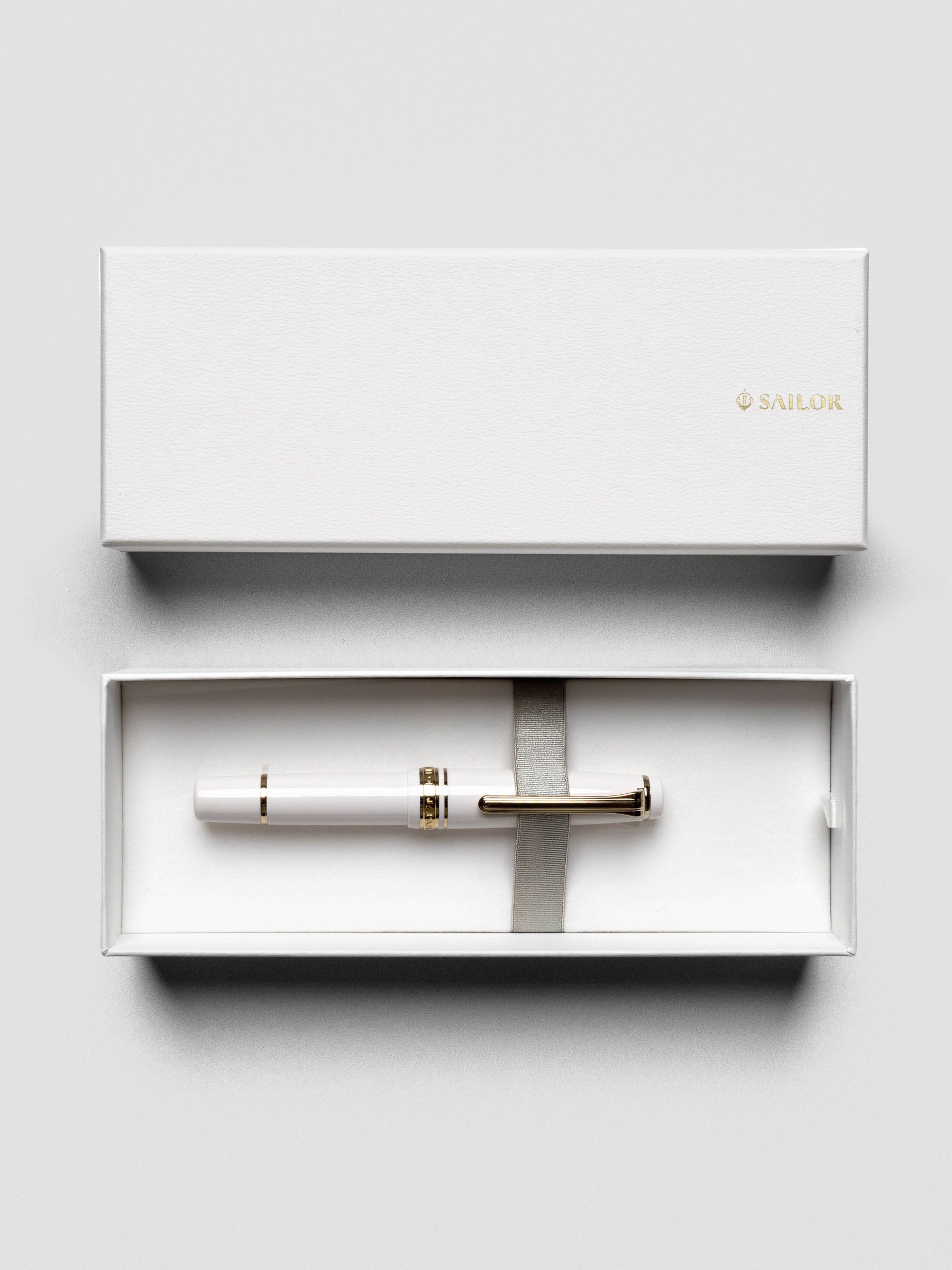 Overhead view of Sailor Pro Gear Slim Mini Fountain Pen in Beni White with cap placed beside.