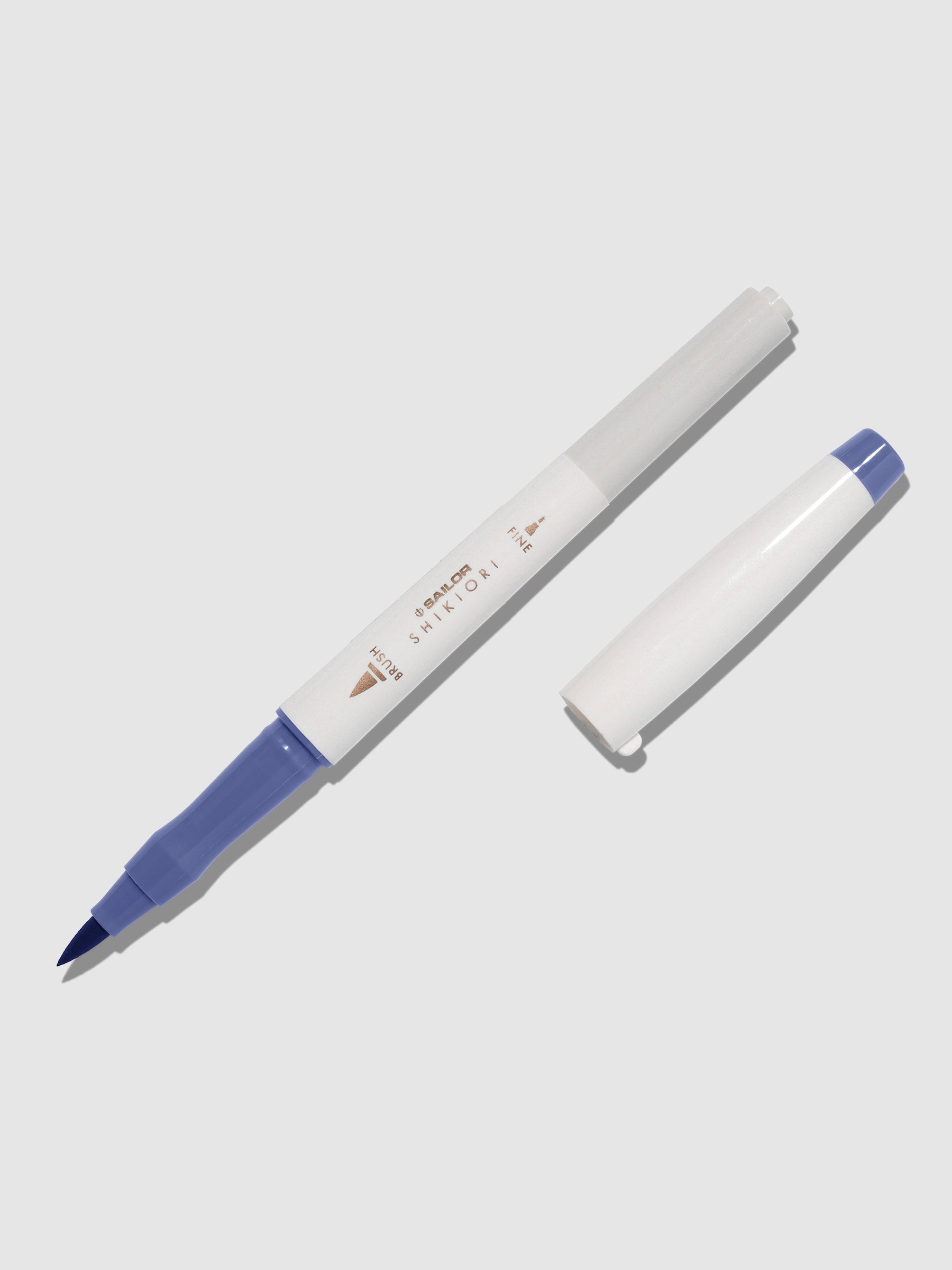 Brush pen displayed on a neutral background. It is uncapped with its brush nib exposed, and the cap lying parallel to the marker. Color pictured is Nioisumire. 