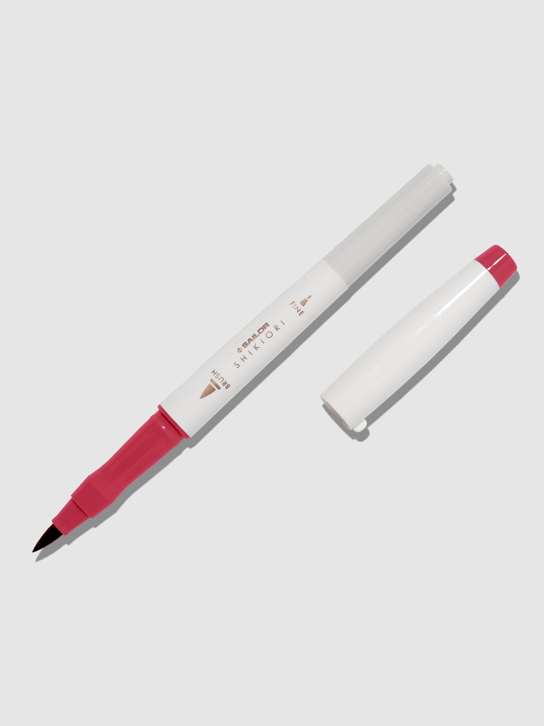 Brush pen displayed on a neutral background. It is uncapped with its brush nib exposed, and the cap lying parallel to the marker. Color pictured is Yodaki. 