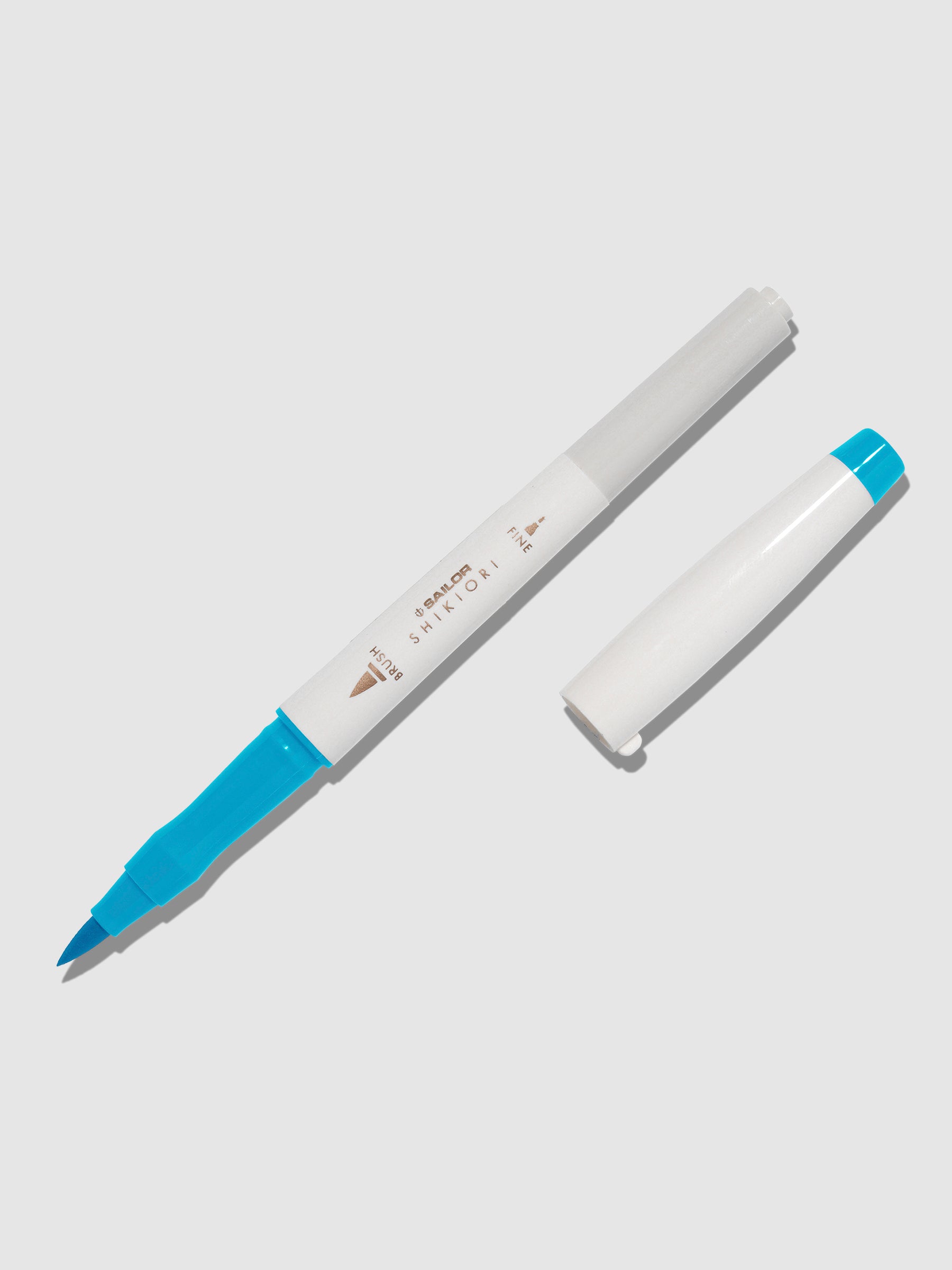 Brush pen displayed on a neutral background. It is uncapped with its brush nib exposed, and the cap lying parallel to the marker. Color pictured is Yukiakari. 