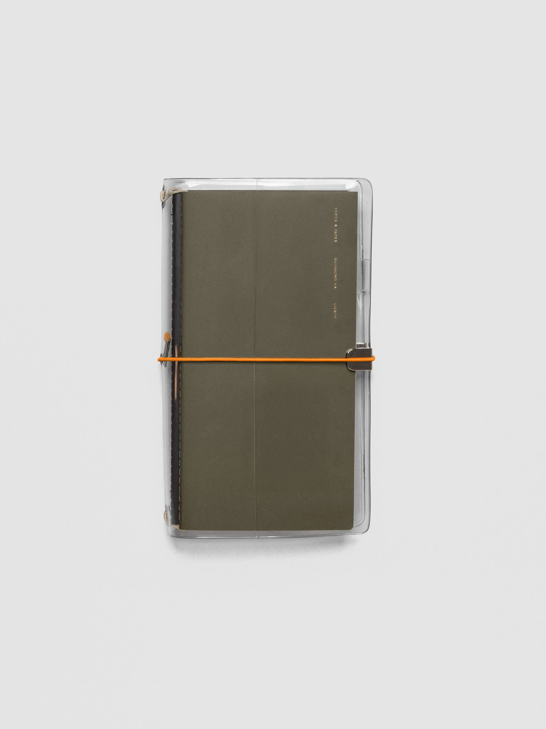 Orange elastic band stretched across clear vinyl cover, anchored at metal clasp.