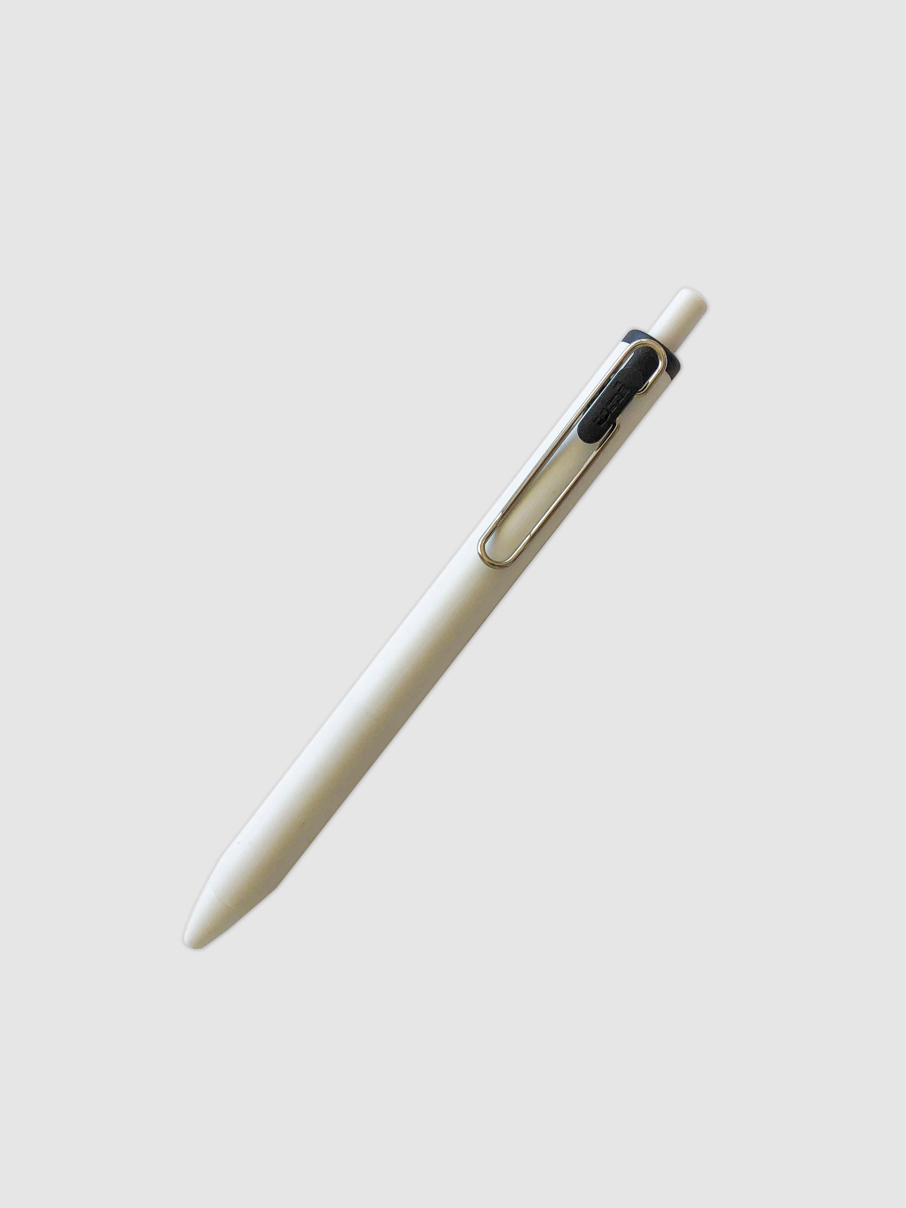Uni-ball One Gel Pen, Black, Cloth and Paper. Pen tilted slightly to the right on a neutral background.