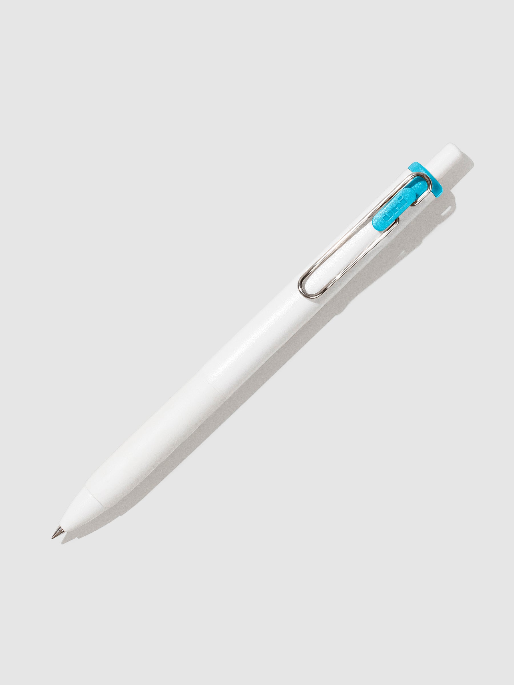 Uni-ball One Gel Pen, Sky Blue, Cloth and Paper. Pen tilted slightly to the right on a neutral background.