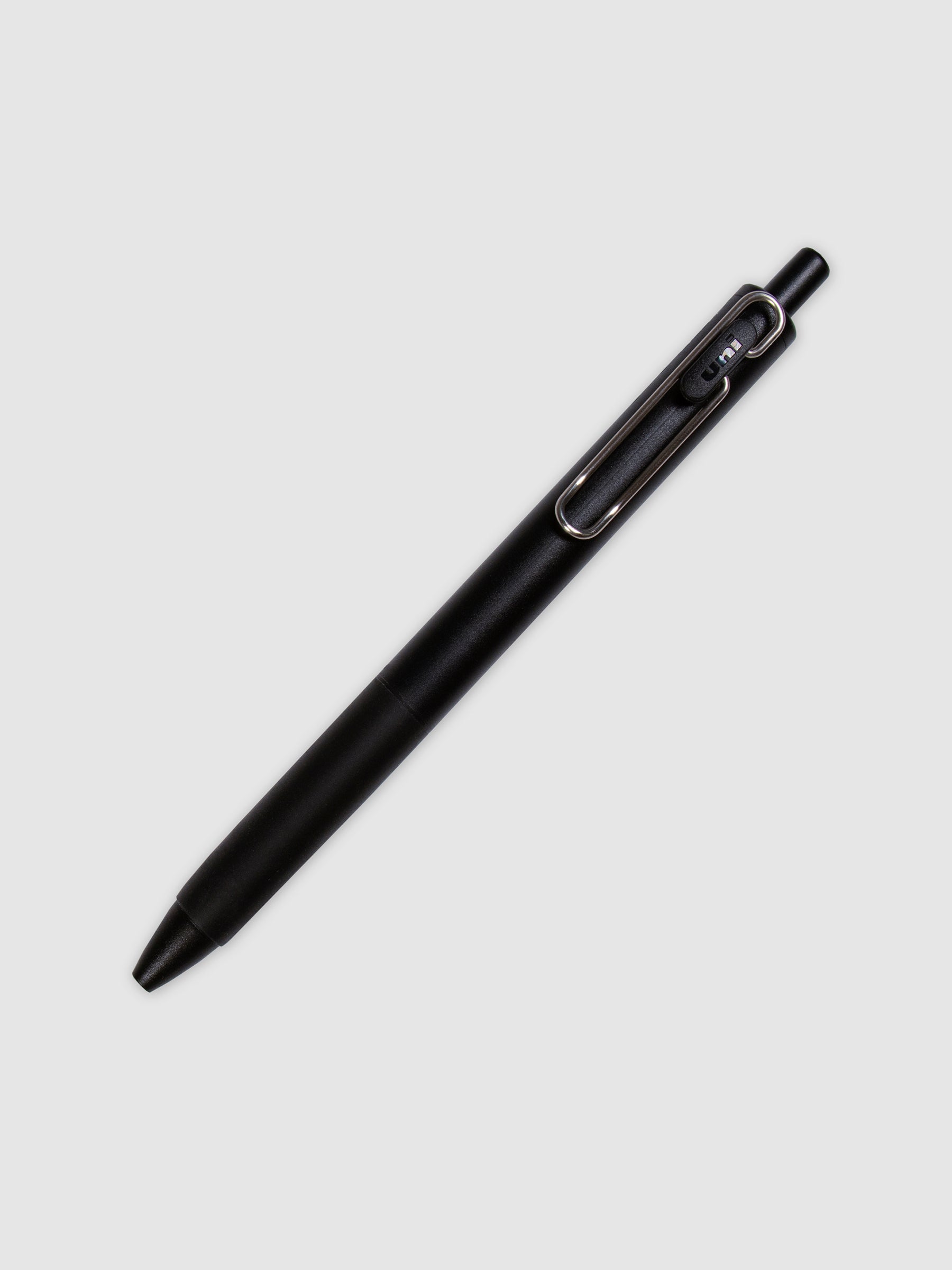 Uni One Gel Pen, 0.38 mm, Black Ink, Black Barrel, Cloth and Paper. Pen turned to the right against a neutral background.