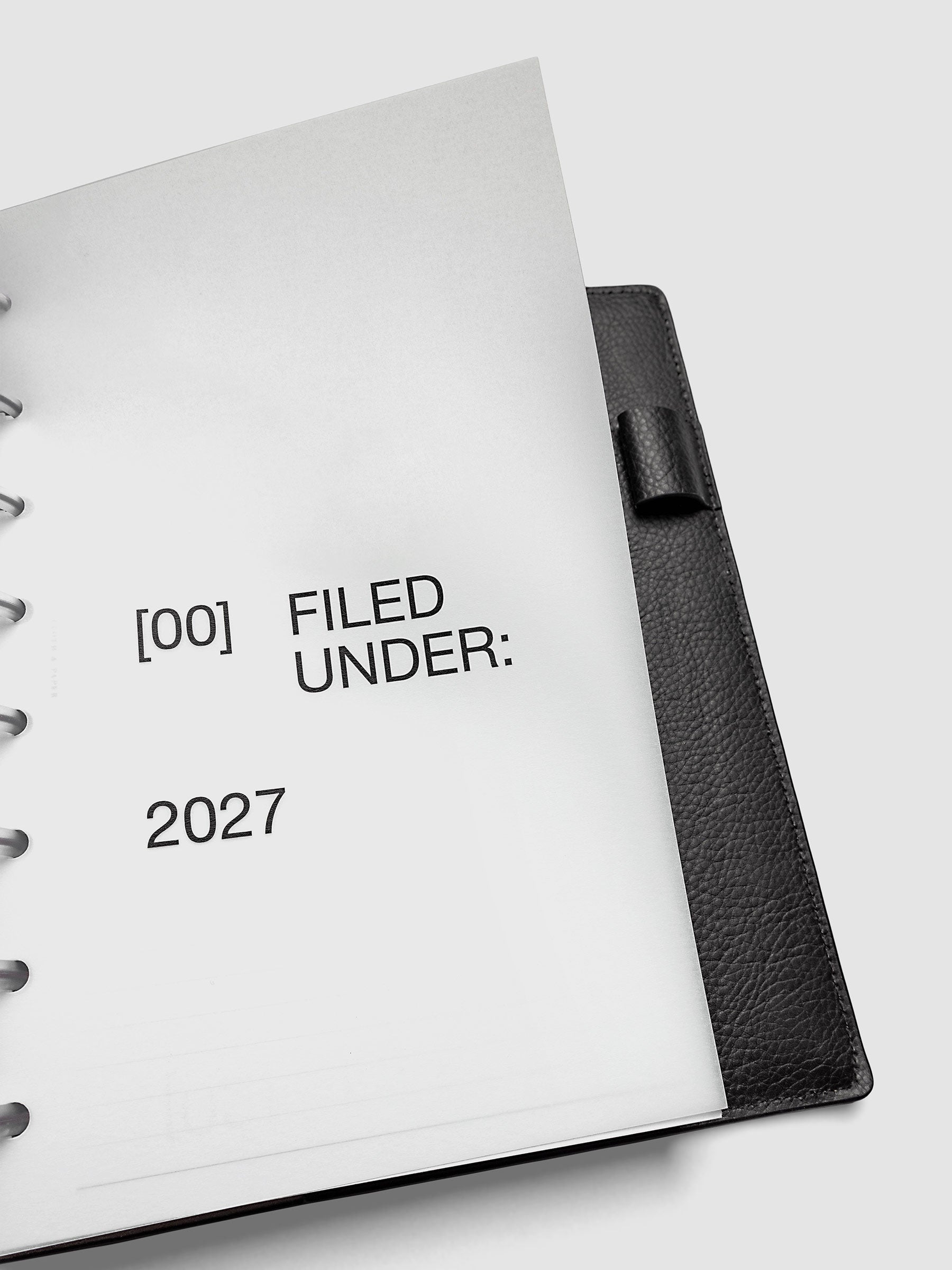 2027 Front + Monthly Dashboard Overlays, Avant Garde, A5 6-Ring Punch, close-up of a vellum dashboard overlay lifted to show the translucent layering effect inside a planner